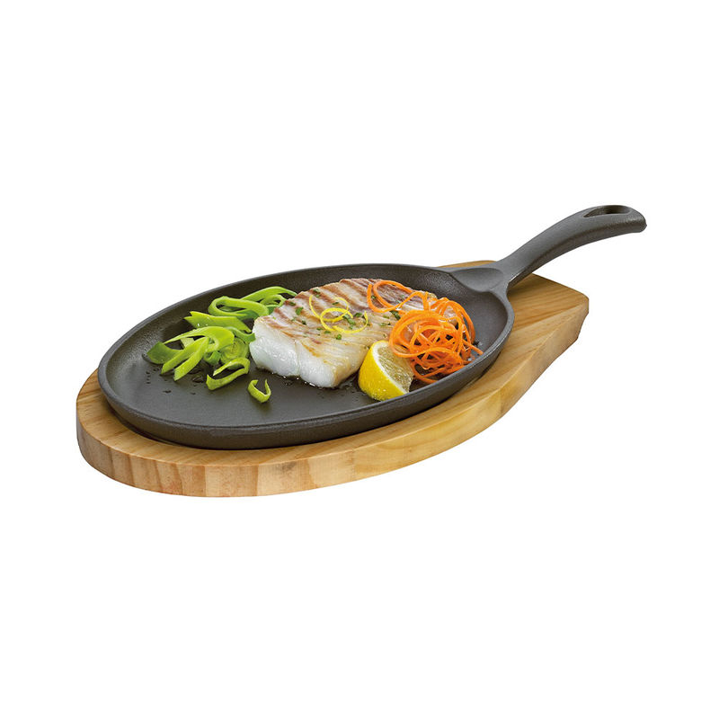 Ovale Gusseisen-Grillpfanne auf Pinienholz-Untersetzer
